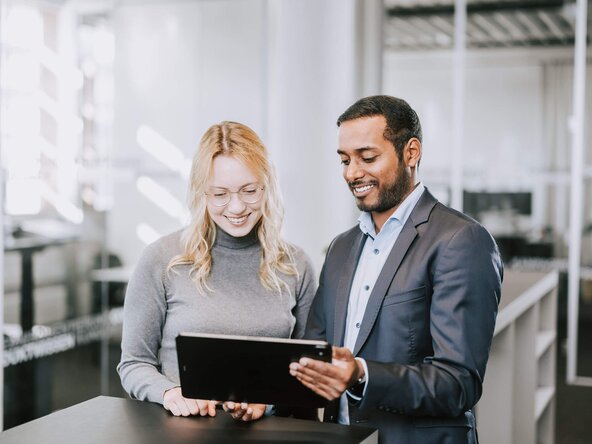Mann und Frau im Büro sehen aufs Tablet