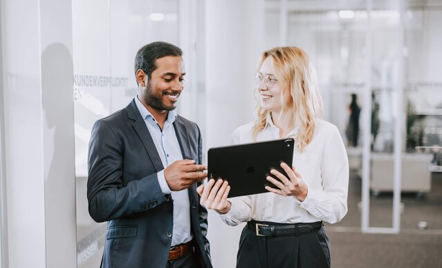 Mann und Frau im Büro sehen aufs Tablet