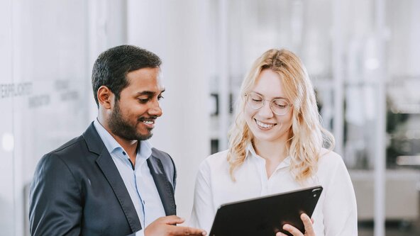 Mann und Frau im Büro sehen aufs Tablet