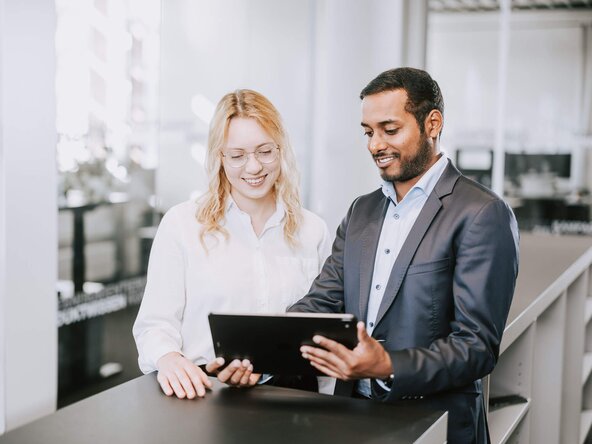 Mann und Frau im Büro sehen aufs Tablet
