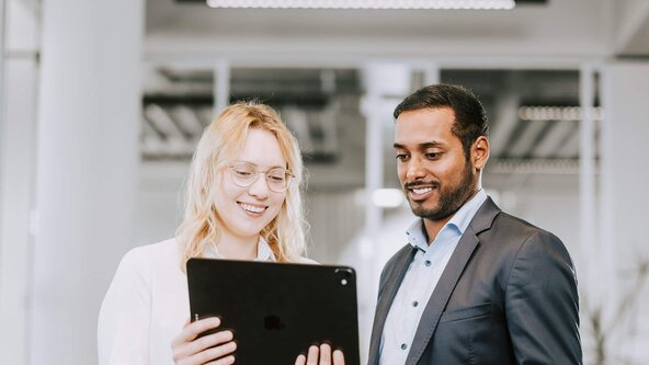 Mann und Frau im Büro sehen aufs Tablet