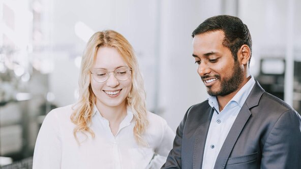 Mann und Frau im Büro sehen aufs Tablet