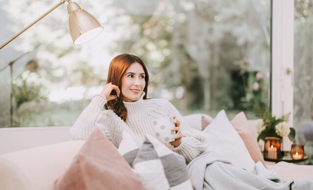 Frau mit Tasse Tee sitzt auf Couch