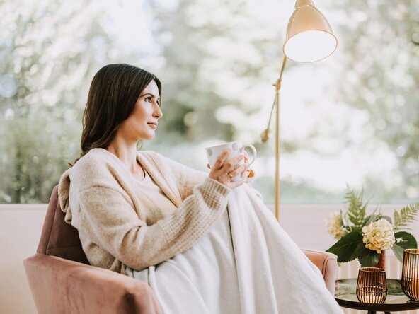 Frau mit Tasse Tee sitzt auf Couch