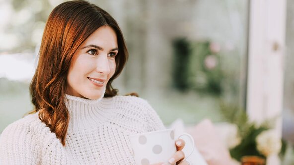 Frau mit Tasse Tee sitzt auf Couch