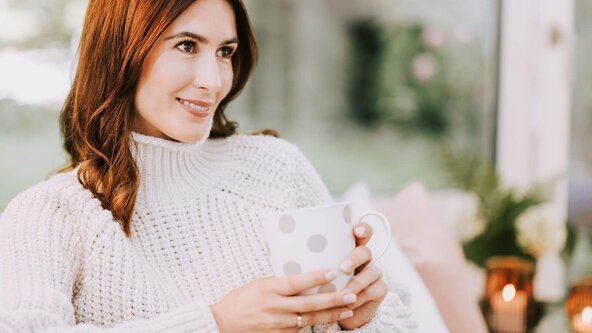 Frau mit Tasse Tee sitzt auf Couch
